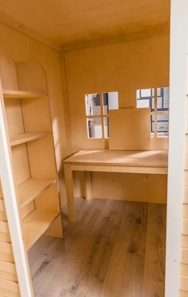 Wooden playhouse interior showing wood floor desk and corner shelving
