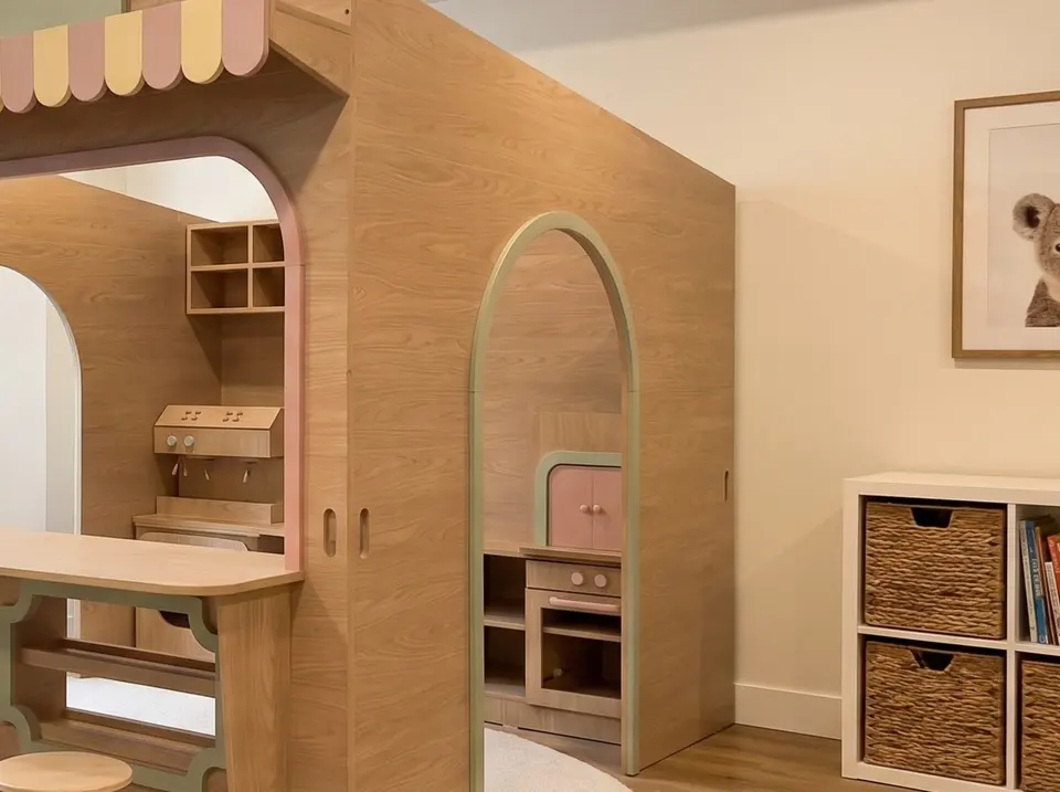 Side profile of wooden indoor playhouse showing arched doorway and play kitchen