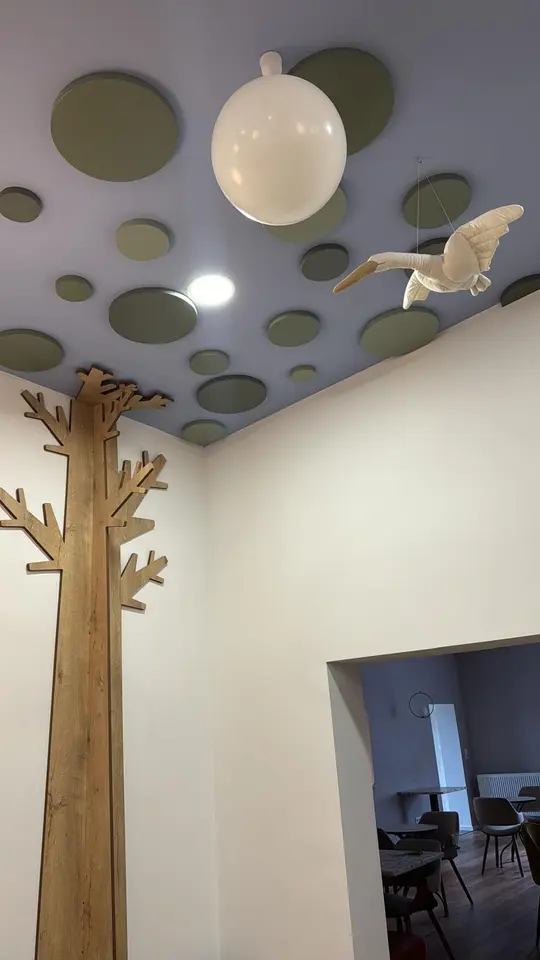 Wall-mounted wooden tree decor and hanging bird ornament in a play cafe
