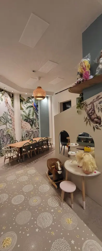 Indoor kids play area with wooden structures, table, and jungle themed wallpaper