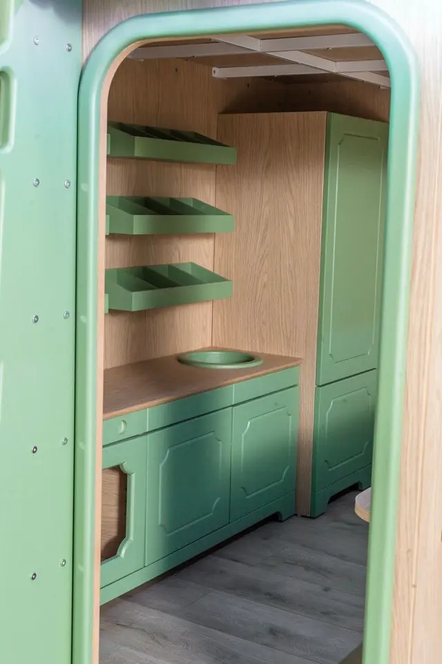 Interior view of playhouse market with green cabinets and wall shelves