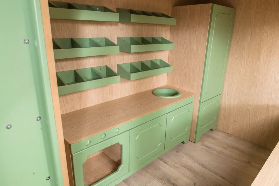 Wooden play kitchen counter with sink, cabinets, tall cupboard, and sorting bins