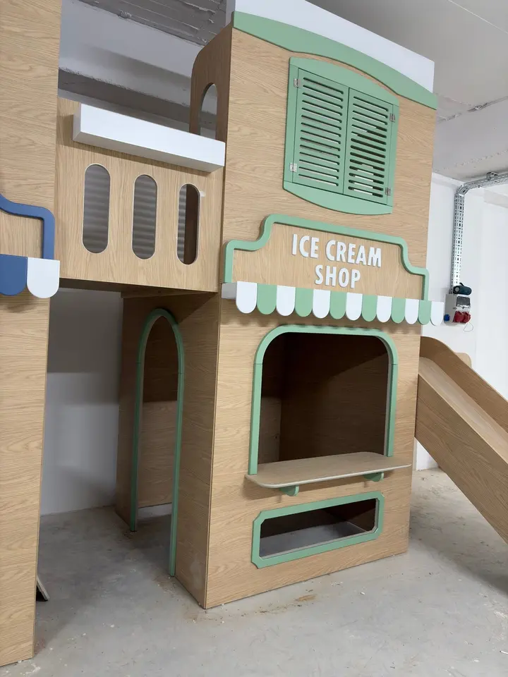 Two-story wooden play ice cream shop with slide in a workshop