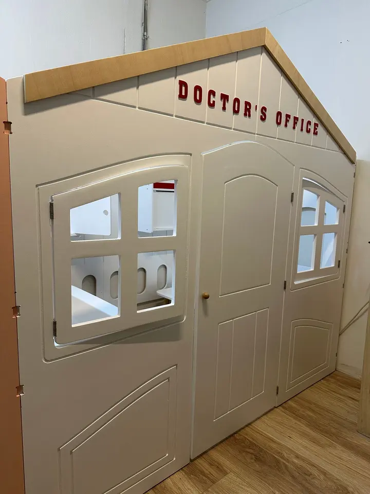White wooden doctor's office playhouse facade with windows and door