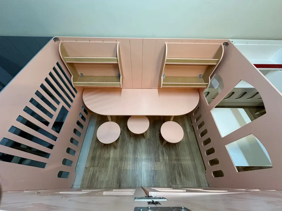 Top view inside pink wooden art studio playhouse with table and stools