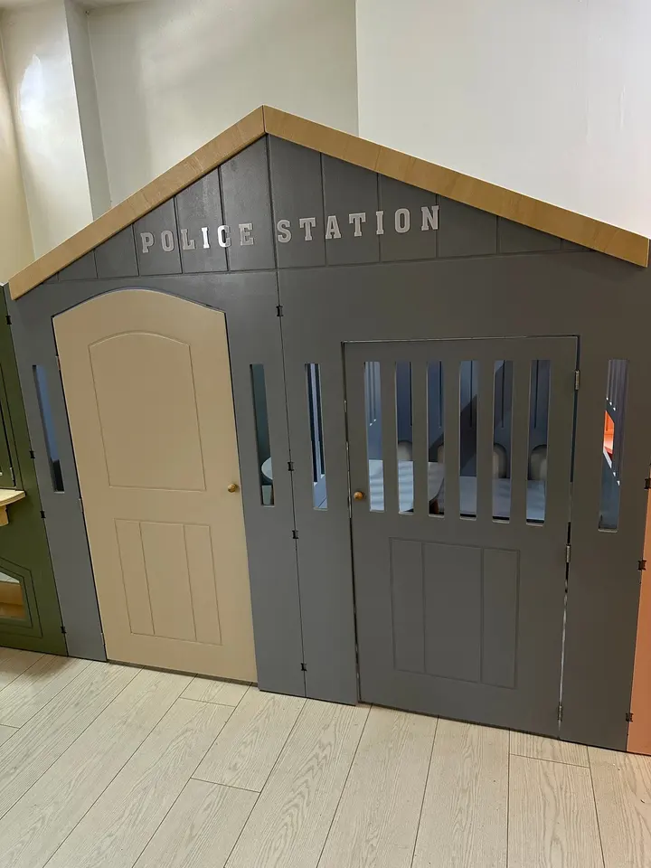 Grey wooden police station playhouse facade with door and barred window