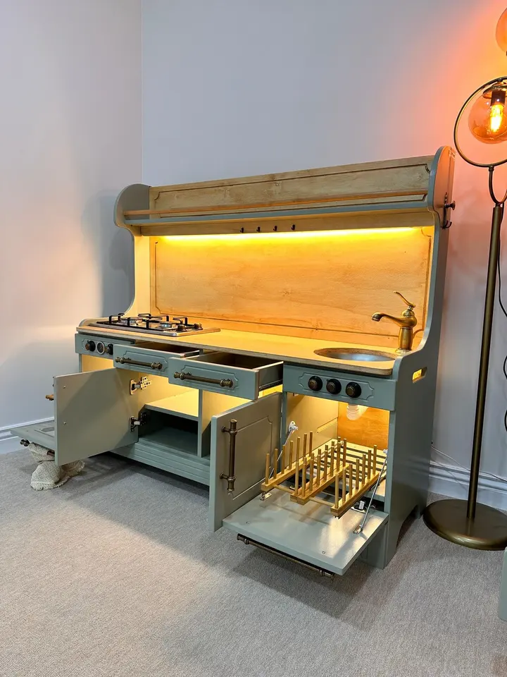 Green wooden play kitchen unit with open cabinets and under-cabinet lighting