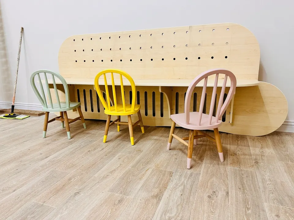 Natural wood wall activity panel and desk with three kids chairs