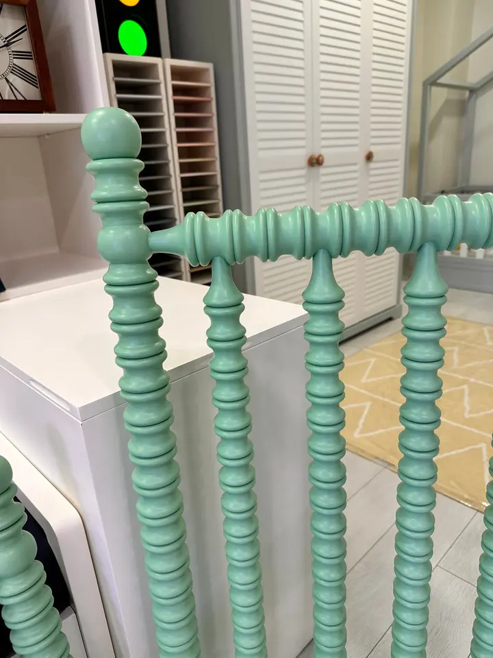 Close-up of a light green turned spindle wood bed rail