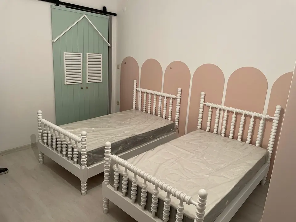 Two white turned spindle single beds beside a green decorative sliding door