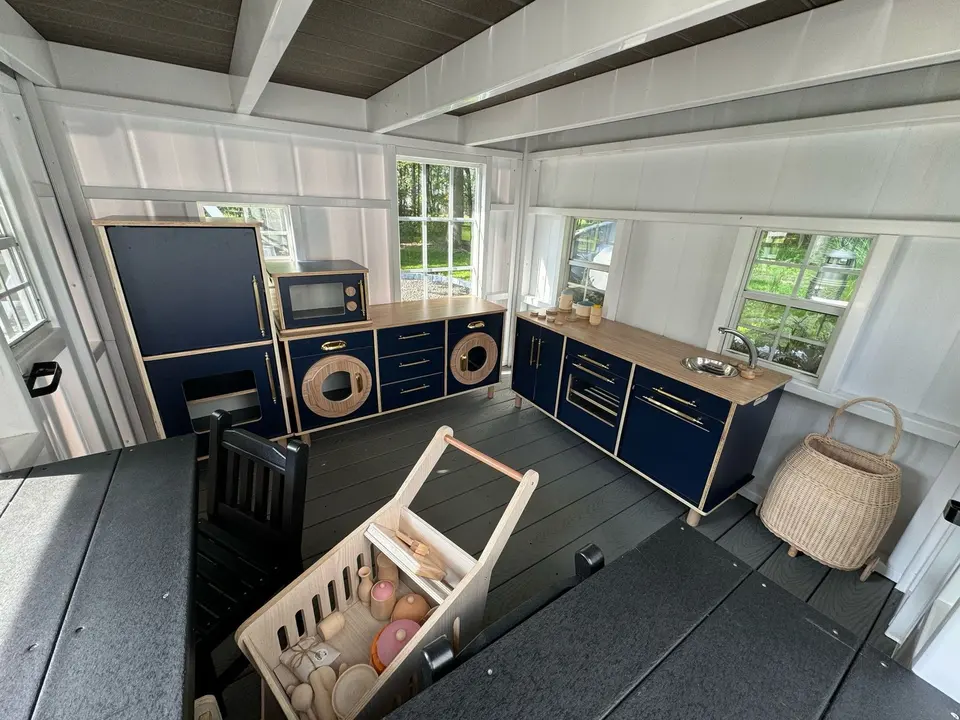 Dark blue kids play kitchen set installed in a playhouse interior