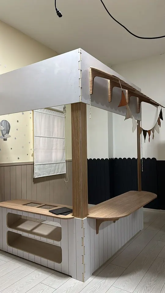 Wooden play kiosk counter with pennant banner inside playroom