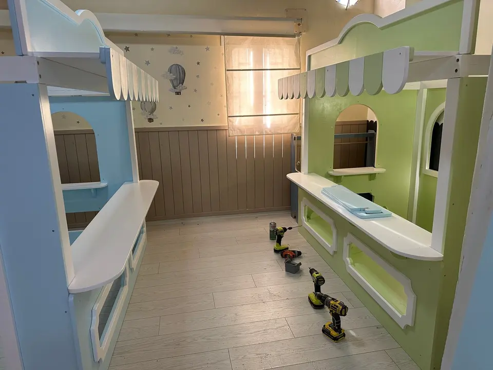Light blue and green wooden play market stalls installed in a playroom