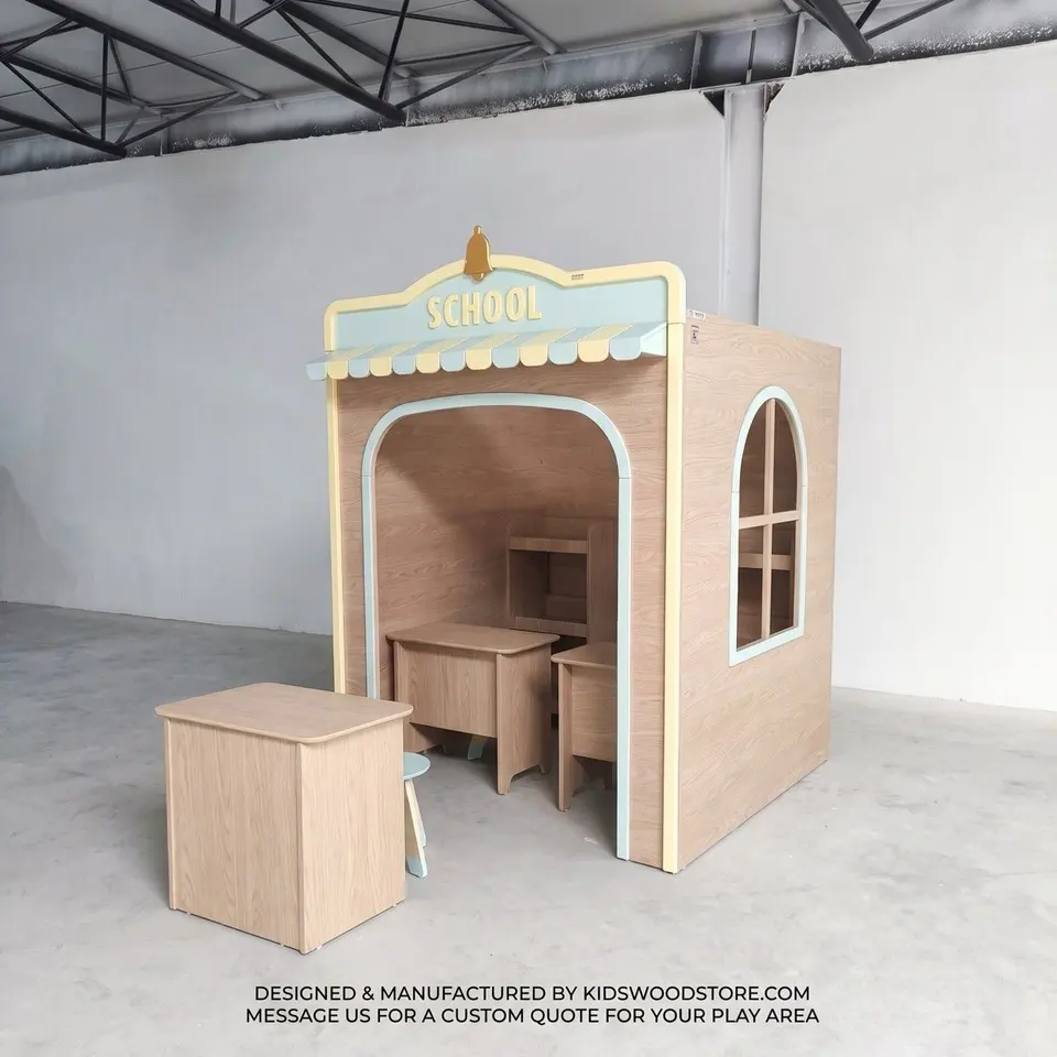 Wooden school playhouse with awning, desks, and small stool in workshop