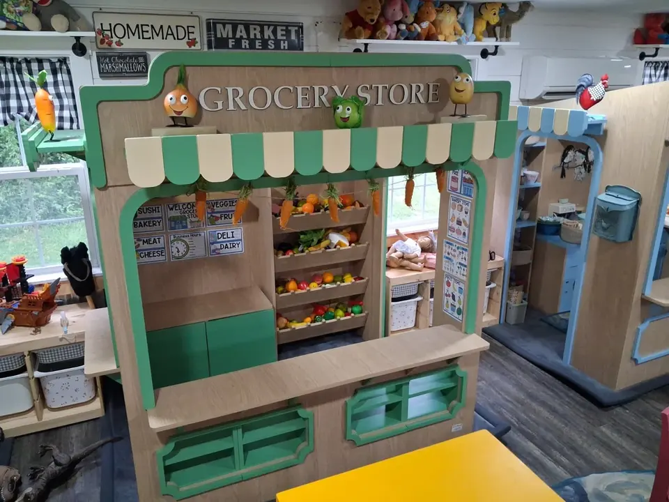 Indoor wooden grocery store play booth with shelves and pretend food