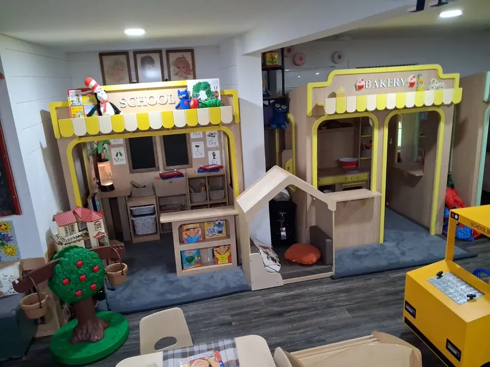 Wooden school and bakery playhouses installed in a playroom setting