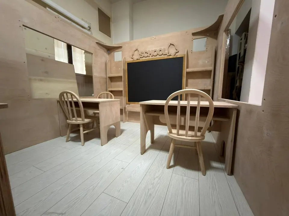 Indoor wooden school playhouse interior with desks, chairs, and chalkboard