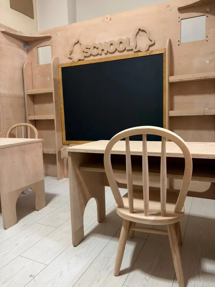 Wooden student desk, chair, and chalkboard inside a school playhouse