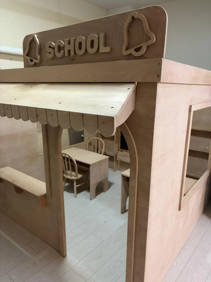 Exterior corner view of wooden school playhouse with awning and interior desks