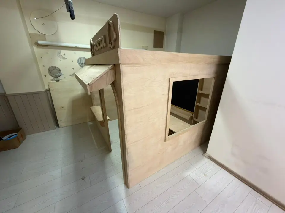 Side view of natural wood school playhouse structure in a room