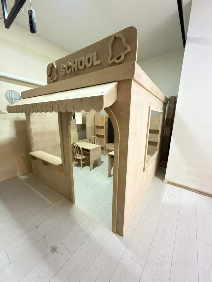Natural wood school playhouse with miniature desks and chairs inside