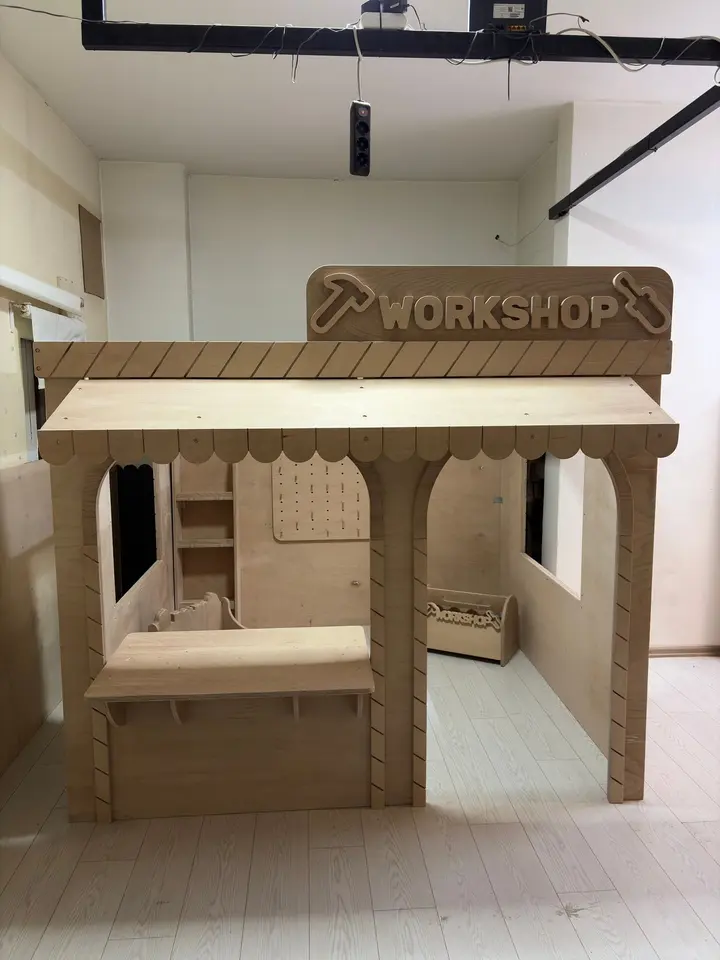 Unpainted wooden workshop themed playhouse with service counter and open doorway