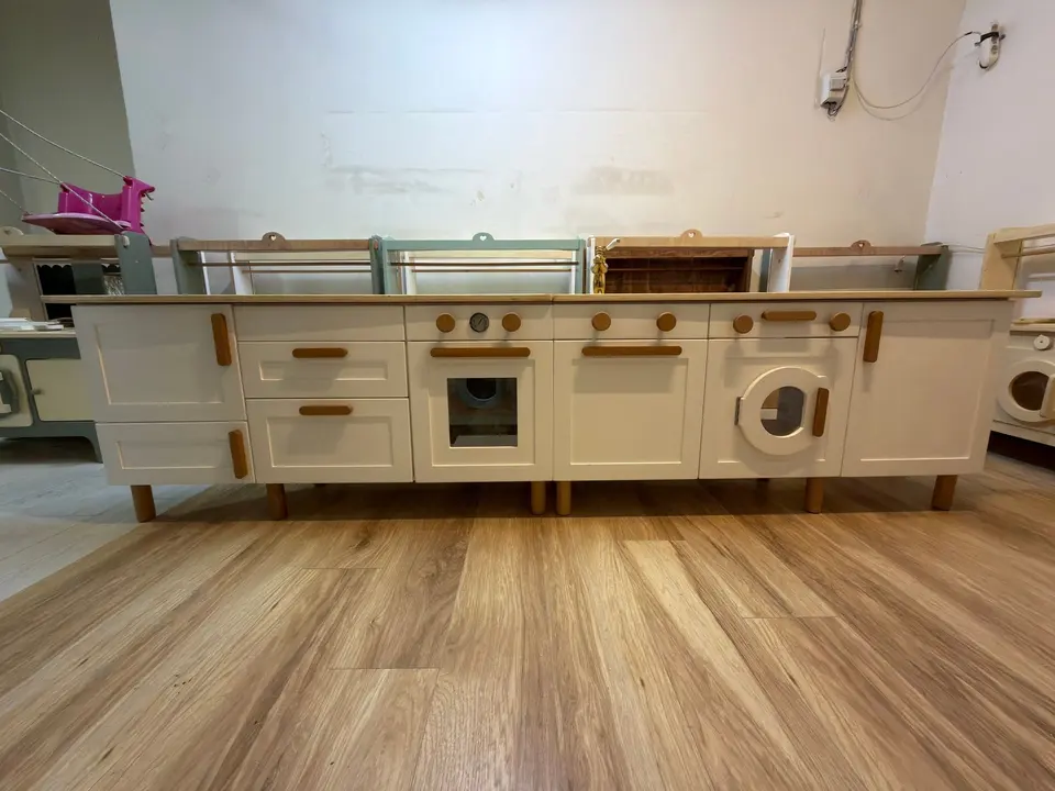 White wooden play kitchen unit with pretend stove and washing machine