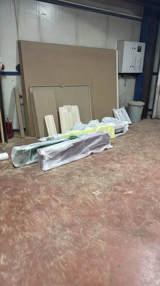 Wrapped wooden playhouse parts and panels leaning against a workshop wall