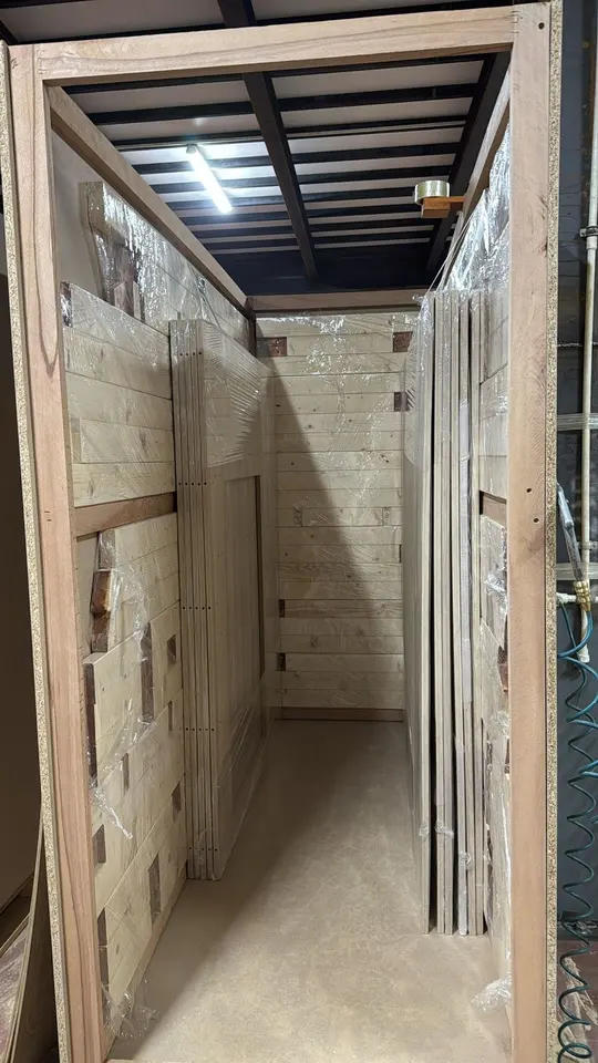 Wooden panels wrapped in plastic film stacked inside a shipping crate