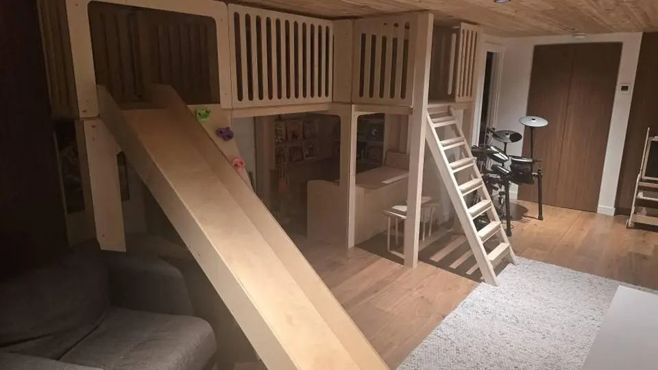 Indoor custom wooden loft playhouse with slide and ladder in a playroom