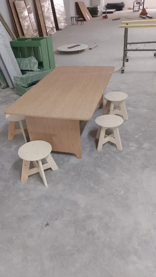 Wooden low activity table surrounded by round wooden stools in workshop