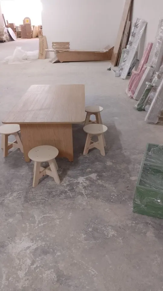 Low wooden kids play table with round stools on workshop floor