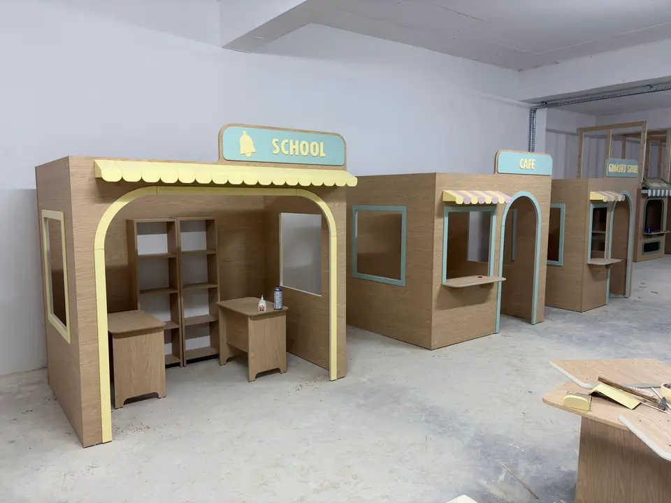Modular wooden playhouse street set with school and cafe kiosks in workshop
