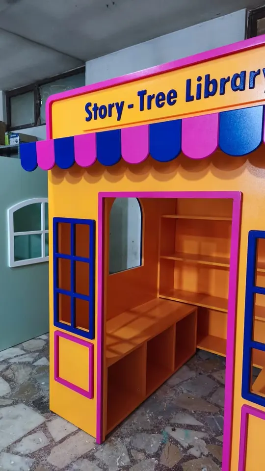 Colorful wooden library playhouse with shelves and bench inside a workshop