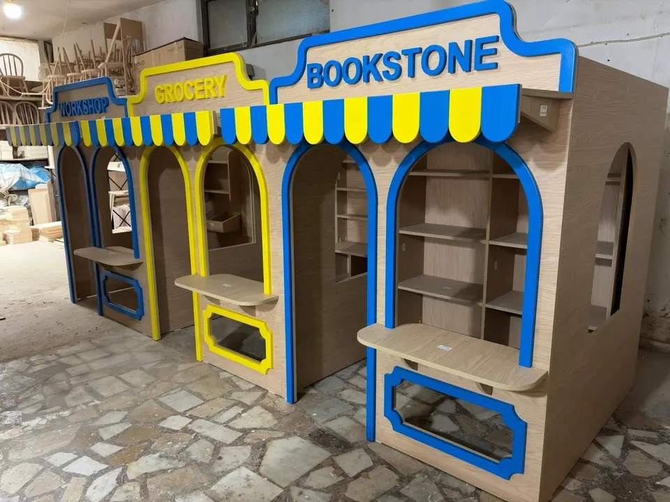 Row of connected wooden play market stalls inside a workshop