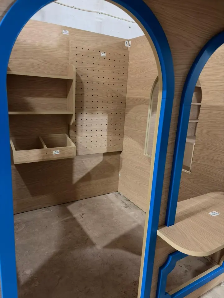 Interior view of wooden playhouse workshop stall with shelves and pegboard