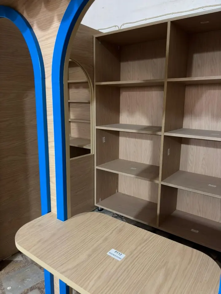 Wooden shelving unit inside play shop stall with blue arched frame