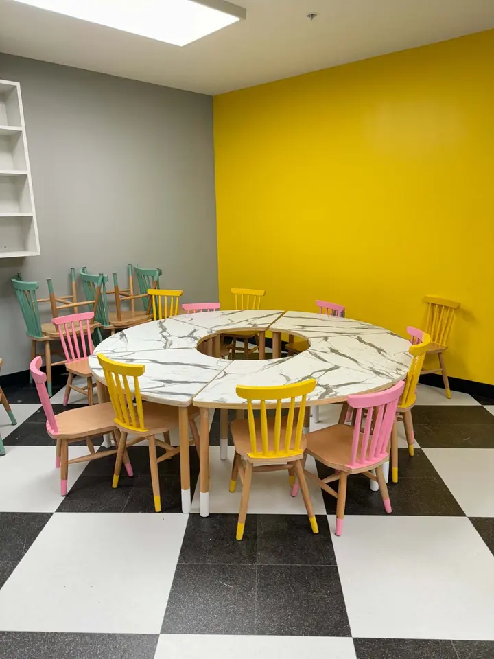 Curved circular kids table with colorful wooden chairs in a bright room