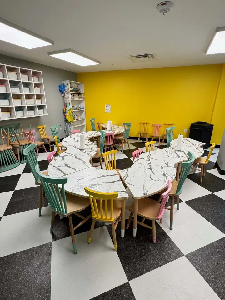 Wavy wooden children table layout with colorful chairs in a play area