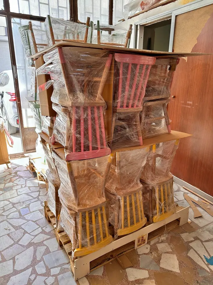 Stack of plastic wrapped wooden chairs packed on a pallet for shipping