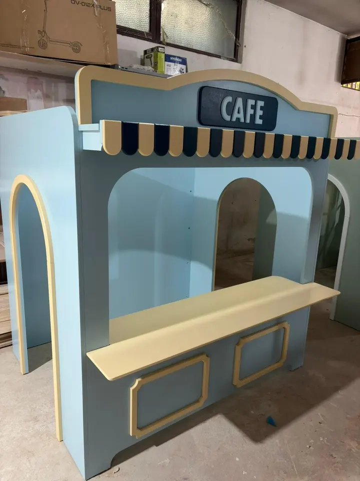 Light blue wooden playhouse cafe stall with striped awning in workshop