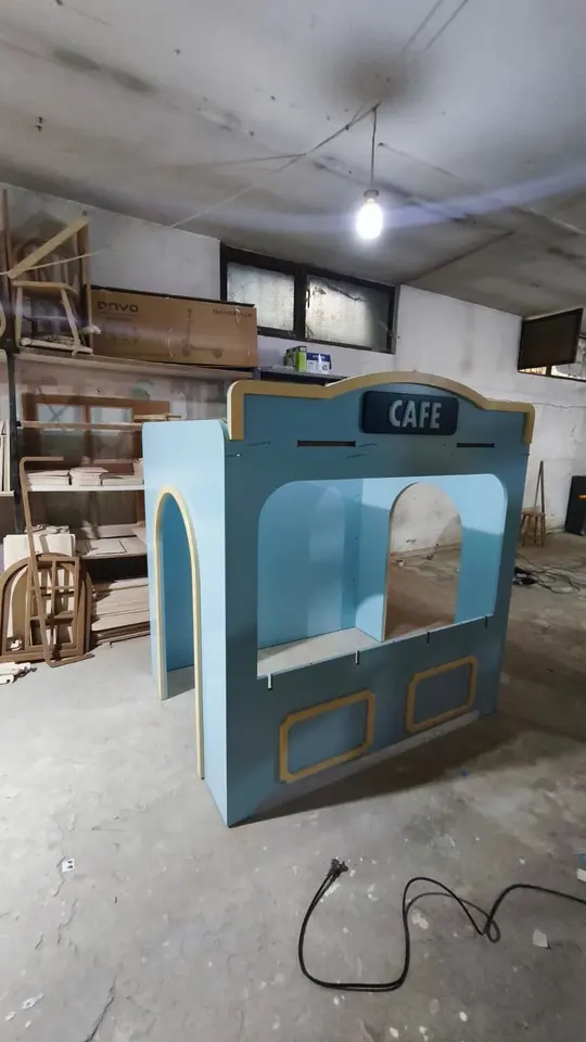 Blue wooden play cafe under construction inside a workshop