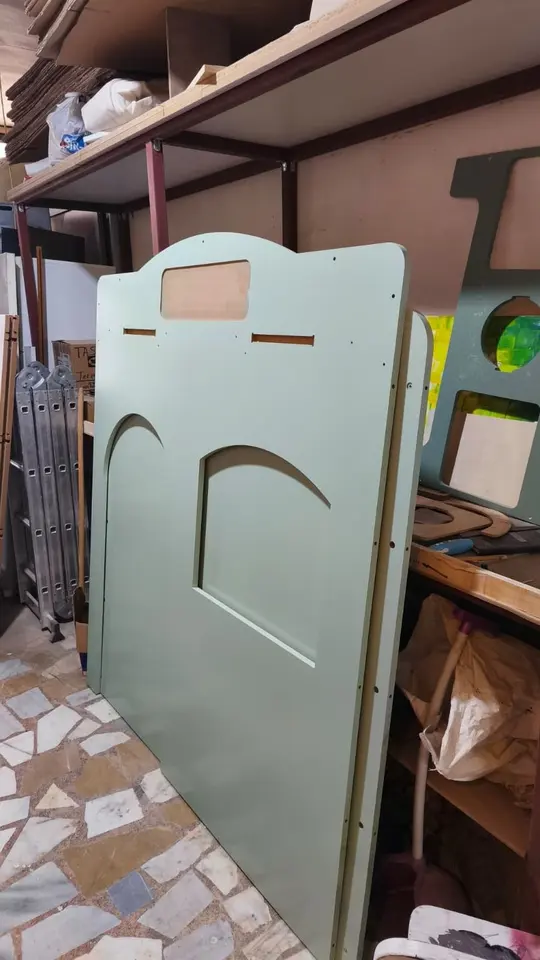 Painted wooden playhouse panels leaning against workshop shelving