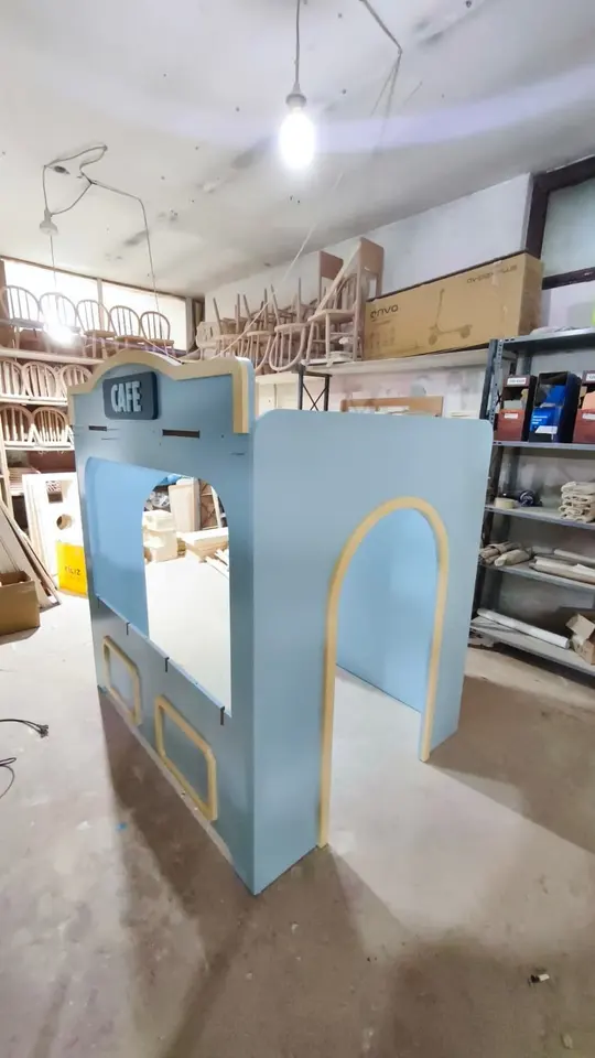 Assembled light blue wooden playhouse booth in a woodworking shop