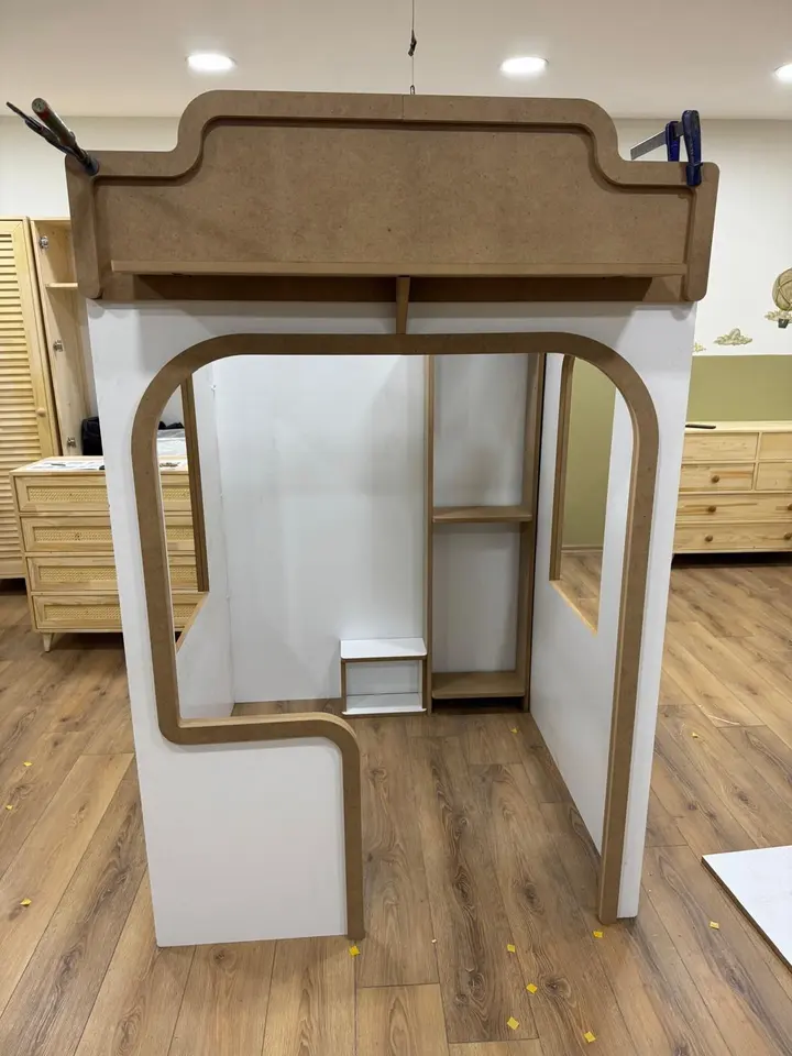 White and raw wood playhouse frame being assembled with clamps