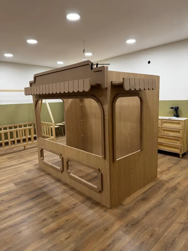 Unfinished wooden kiosk playhouse assembled in a workshop showroom setting