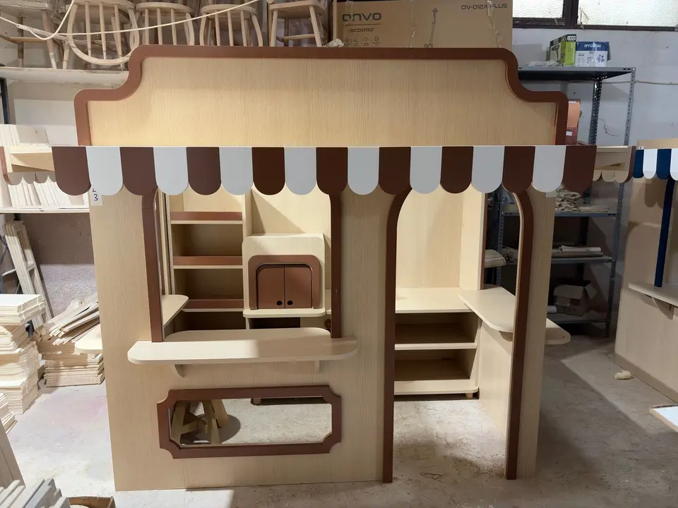 Wooden play market stall with brown striped awning in workshop