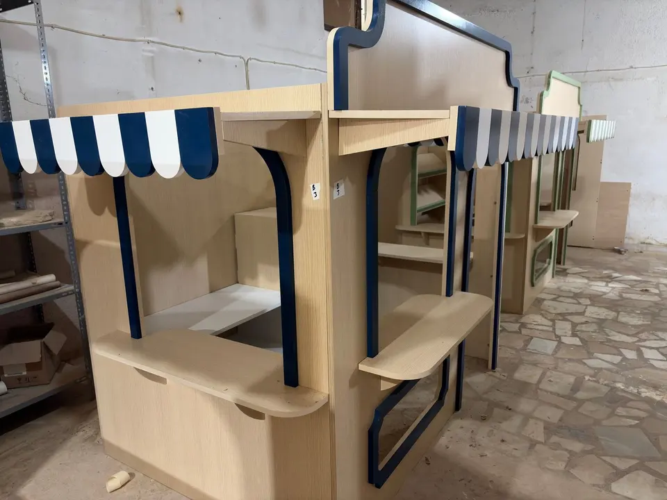Side view of wooden children play stalls lined up in workshop