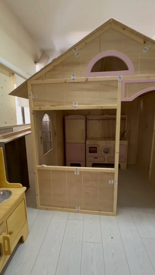 Wooden indoor playhouse structure with toy kitchen set inside workshop