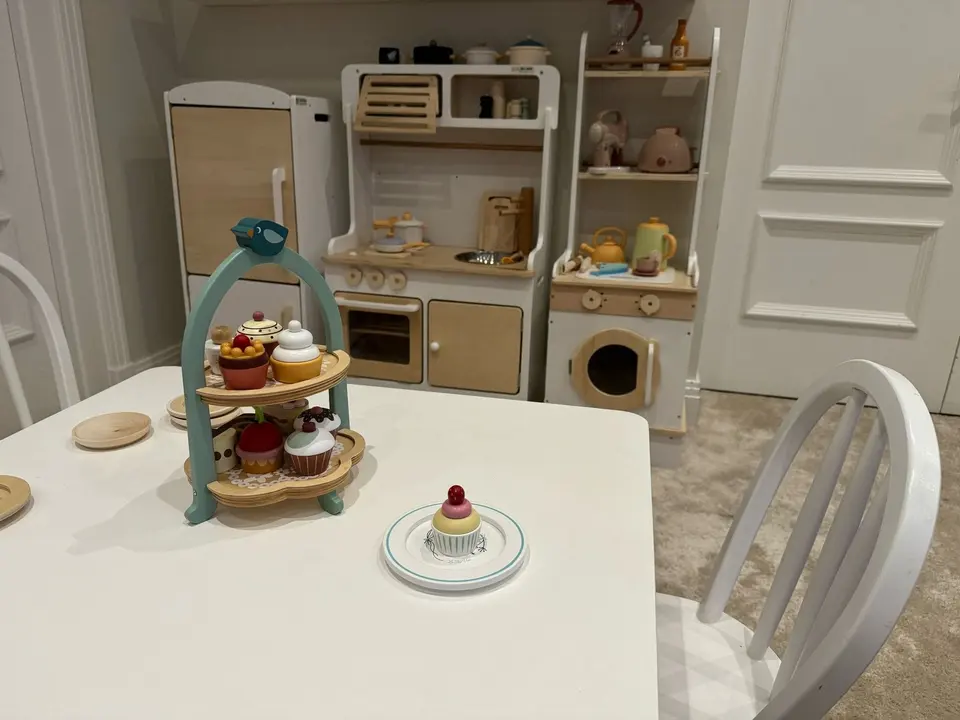 Kids play kitchen and tea set on child table in playroom